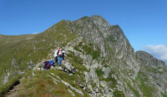 Christian und Codruta sitzen auf einem Stein auf dem Bergsattel