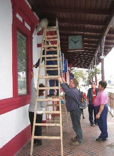 Mann steht auf Leiter umgeben von drei Helfern