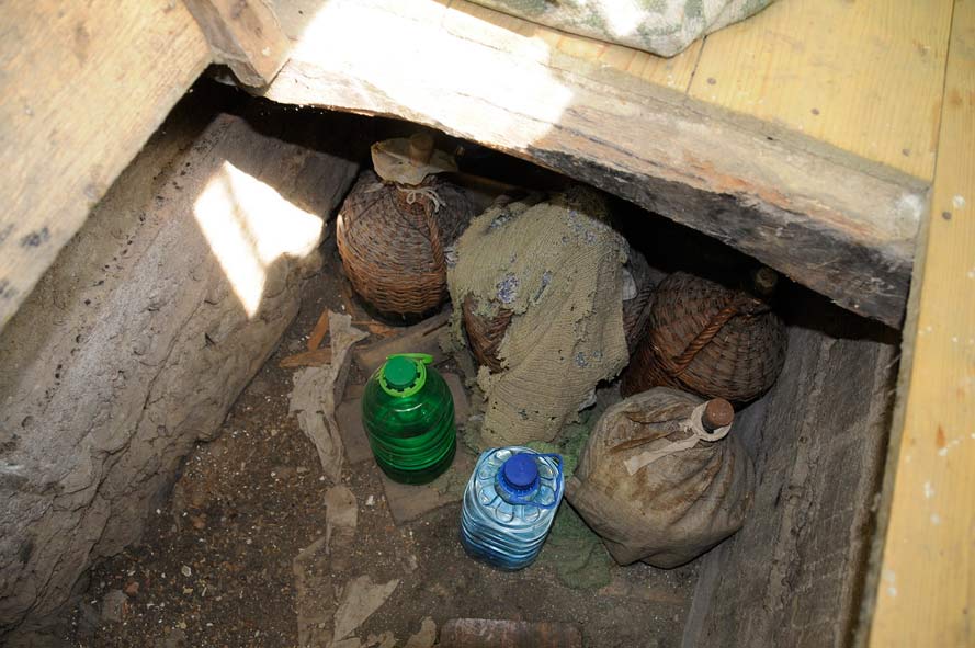 Plastegefäße und holzummantelte Glasbehälter stehen in einem Versteck unter dem Fußboden