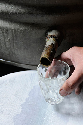 fertiger Schnaps fliesst aus einem Rohr im Fass in eine Glas