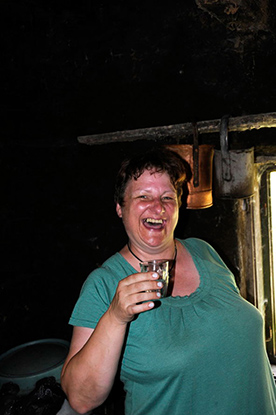 Frau hält lachend ein Schnapsglass in der Hand