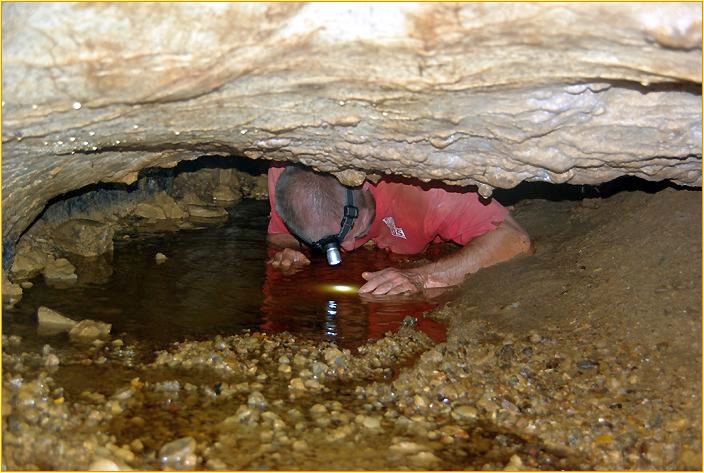 Mann kriecht durch enge Stelle in Höhle
