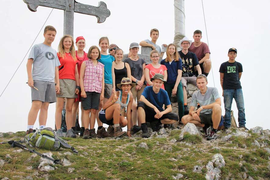 Jugendlich stehen vor einem Gipfelkreuz