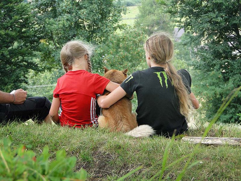 zwei Kinder umarmen einen Hund
