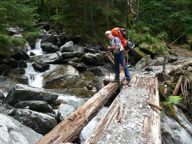 Christian steht auf einer Holzbrücke aus mehrern Holzbohlen bestehend ohne Geländer