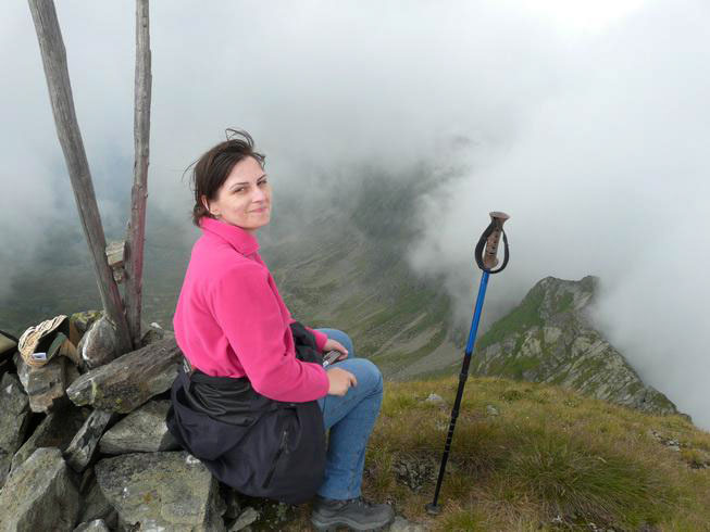 Codruta sitzt auf dem Gipfelsteinen und schaut fröhlich in die Kamera