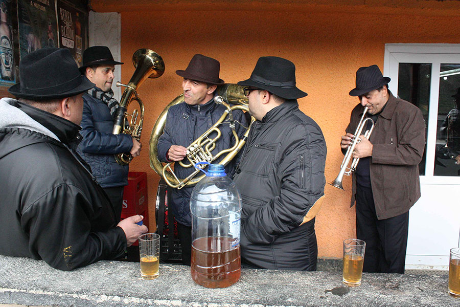 Männer stehen mit ihrem Instrumenten vor einem Hauseingang und unterhalten sich