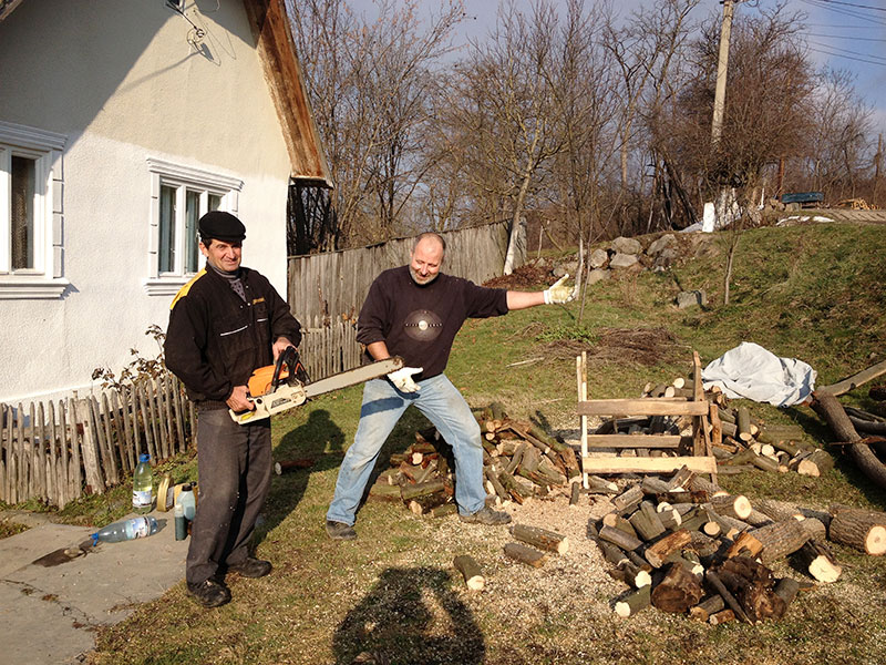 Hellas Mann und Nachbar mit Kettensäge vor einem Holzstapel