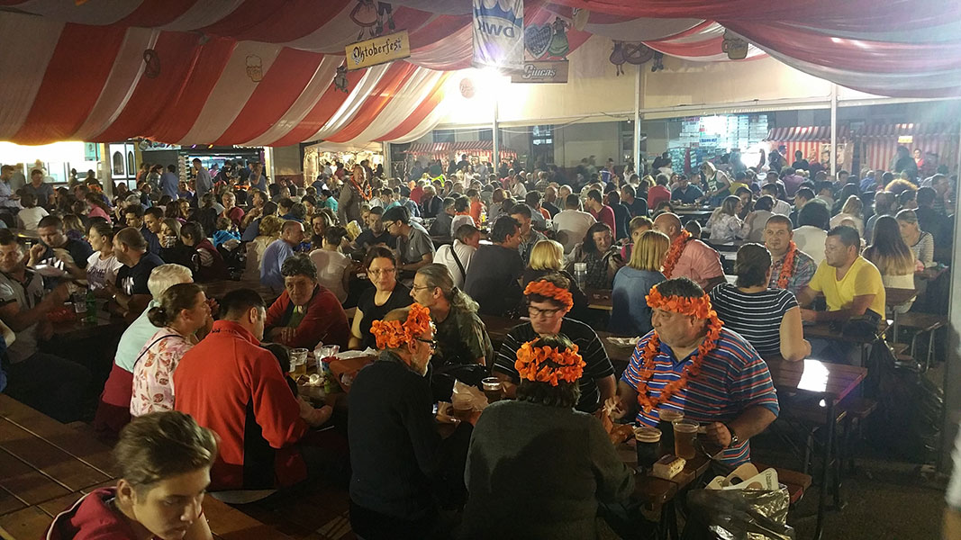 Festzelt gefüllt mit vielen Menschen welche an Biertischen sitzen