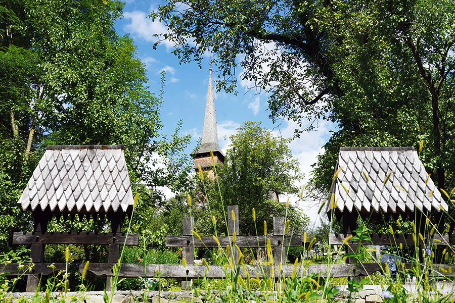 Turm einer Holzkirche hinzer einem verzierten Holzzaun