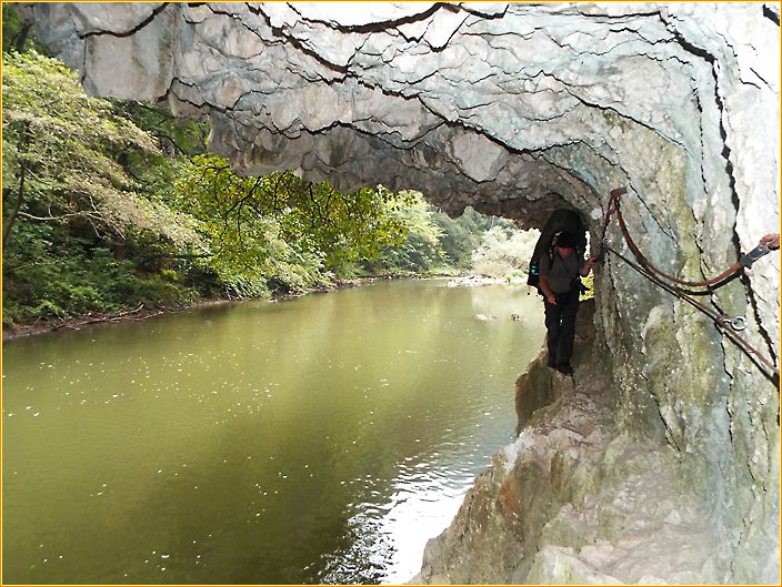 Hans wandert an einem schmalen Weg an einem Seil