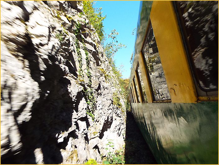 Zugwaggon fährt sehr nahe an einer Felswand vorbei