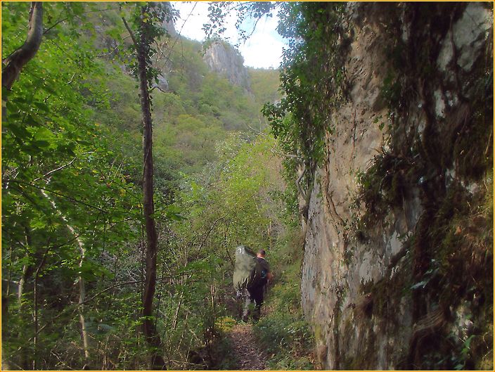 Wanderer auf einem schmalen Pfad mit großem Rucksack