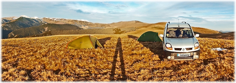 Zwei Zelte stehen auf einem Bergplateau vor einer weitläufigen Berglandschaft