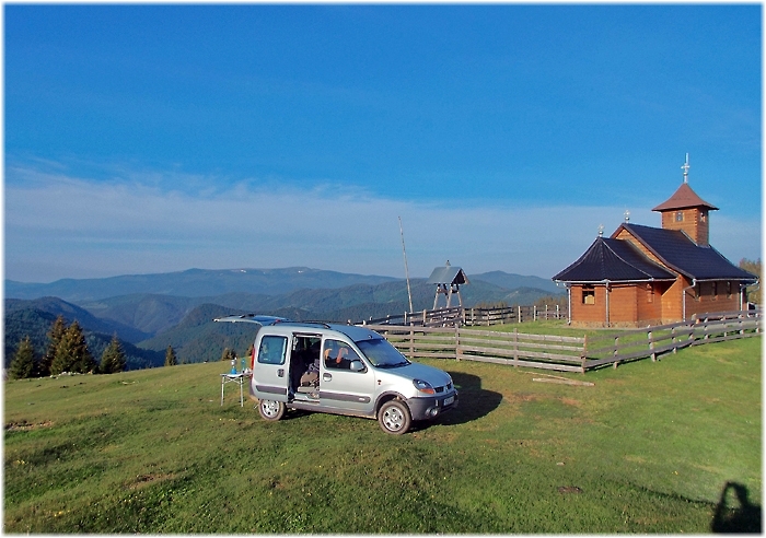 Auto steht auf einem Hügel vor einer Holzkirche