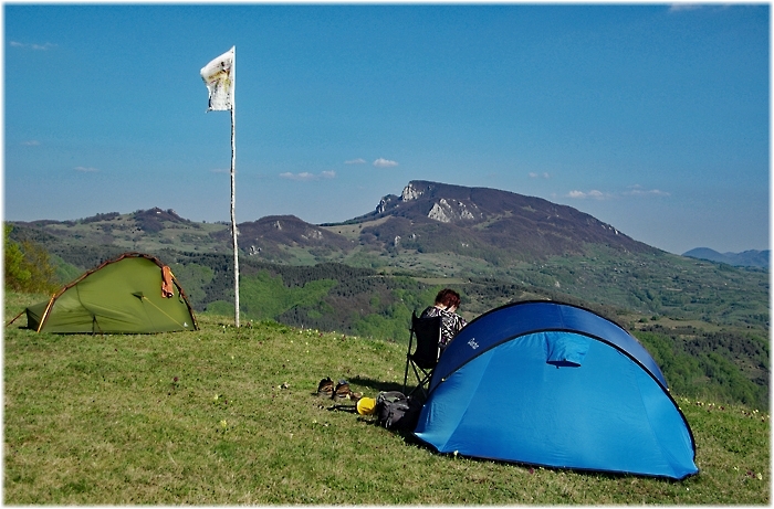 Zwei Zelte stehen auf einer Bergkuppe mit Blick auf Täler und bewaldete Bergkämme