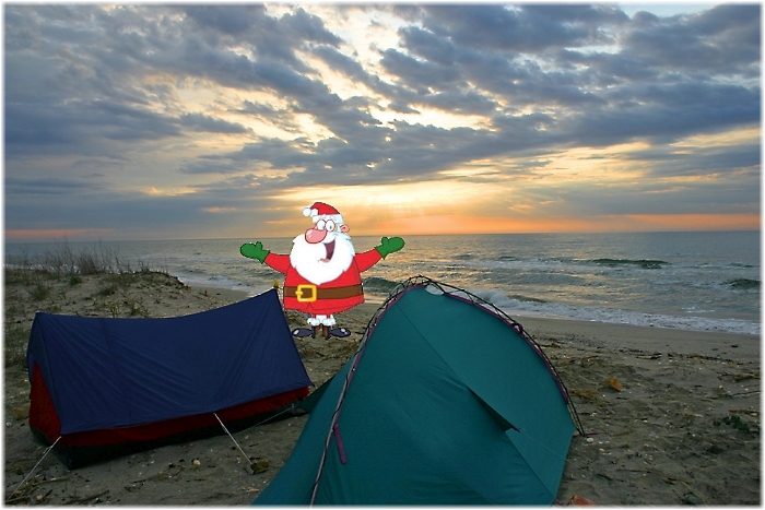 Weihnachtsmann steht vor zwei Zelten am Meer