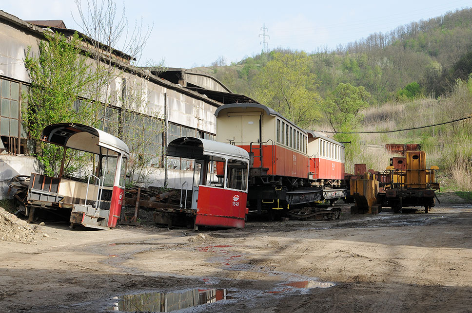 alte Waggons und abgeschnitten Kopfteile einer Straßenbahn stehen auf dem Betriebsgelände