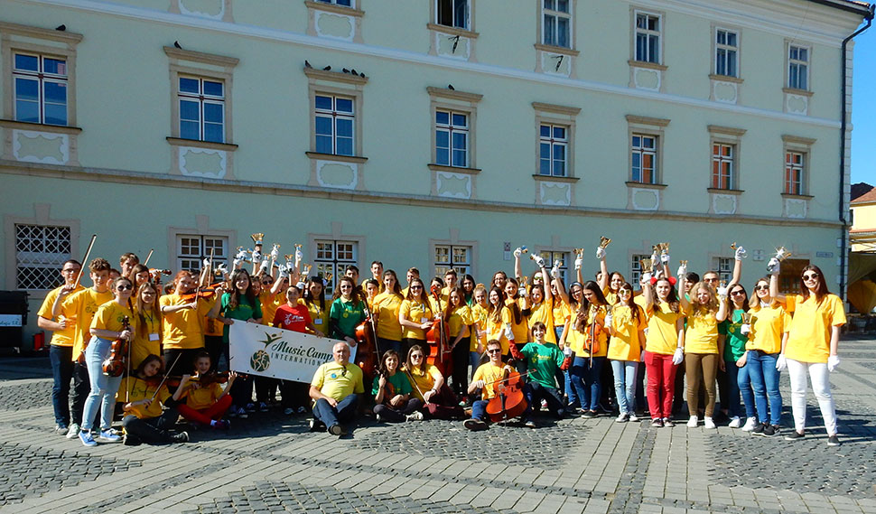 Kinder stehen für ein Gruppenfoto mit gelben T-Shirts auf dem Marktplatz in Sibiu