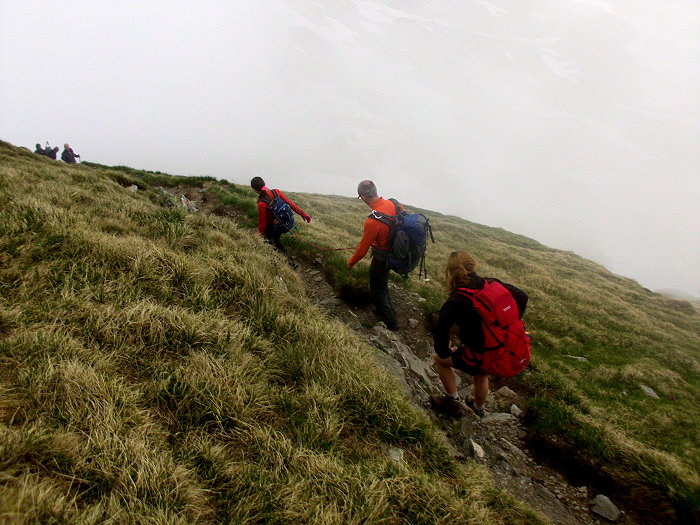 Bergwanderer laufen auf einem schmalen Weg im Nebel