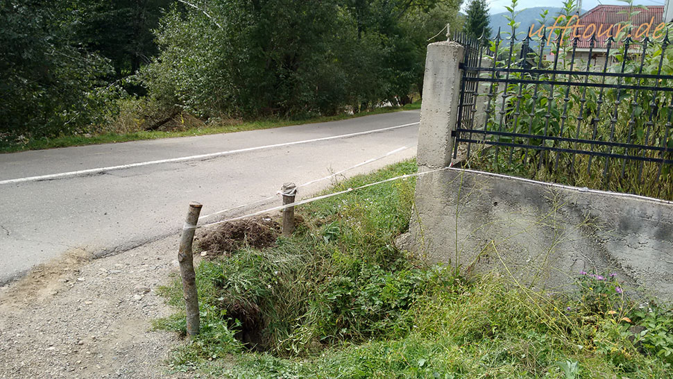 Zwei Äste und ein weißer Strick speeren das Loch neben der Straße ab