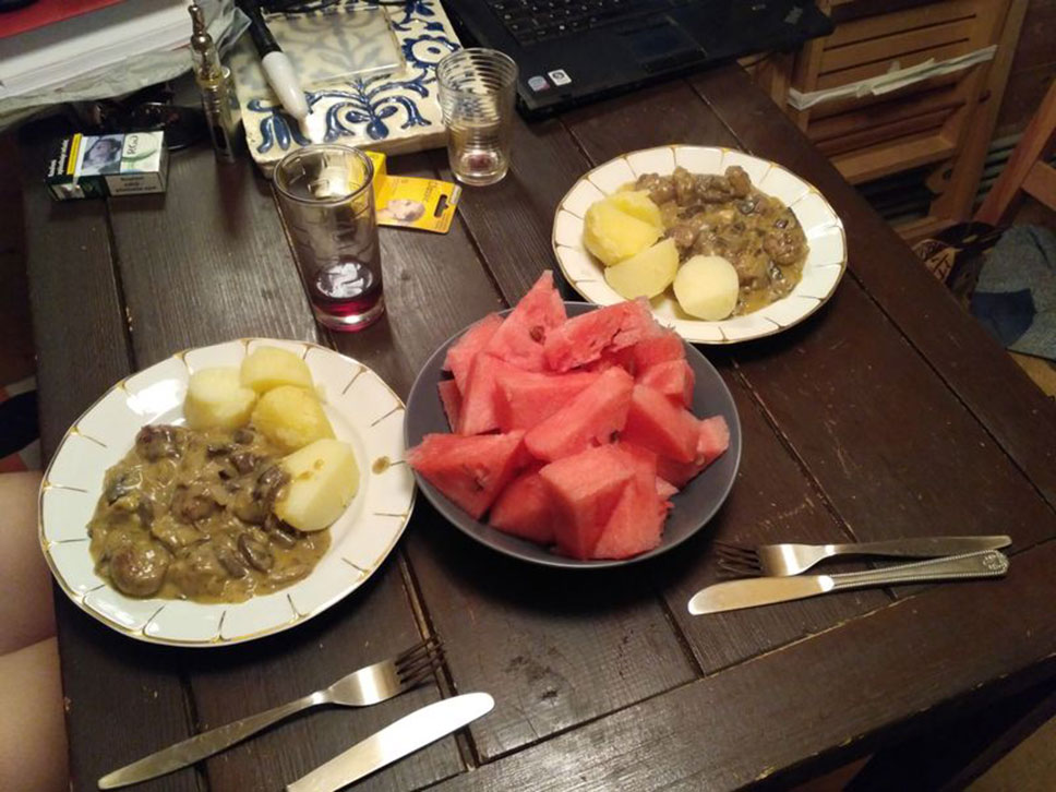 gedeckter Essentisch mit zwei Tellern gefüllt mit Kartoffeln und Pilzen sowie einem Teller mit kleinen Melonenstücken