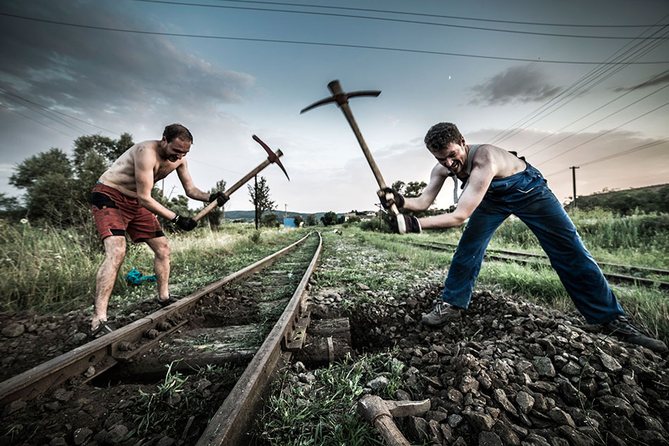 zwei Männer arbeiten mit einer Hacke am Gleis