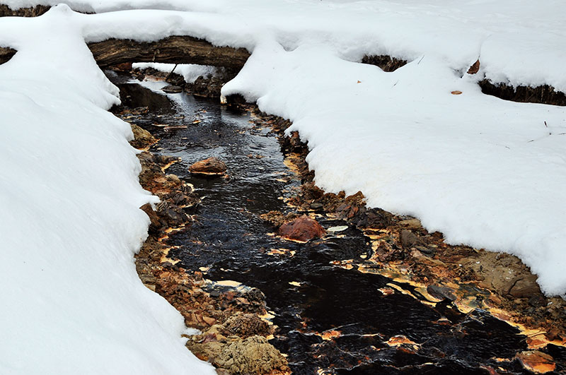 das schwarze Flusswasser eingerahmt von weißem Schnee