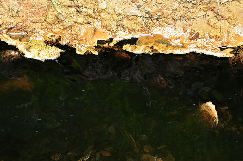 schwarzes Wasser mit gelblichem Ufersteinen