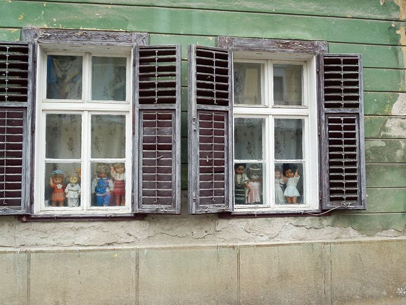 Nahaufnahme von zwei Fenstern mit Puppen hinter dem Fensterglas