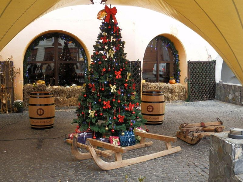 geschmückter Weihnachtsbaum mit Holzschlitten davor