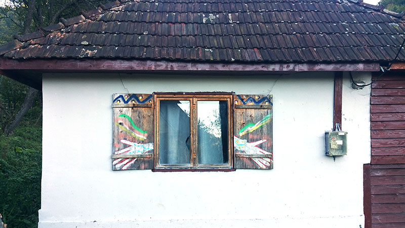 weis bemalte Hauswand mit bunt bemalten Fensterläden