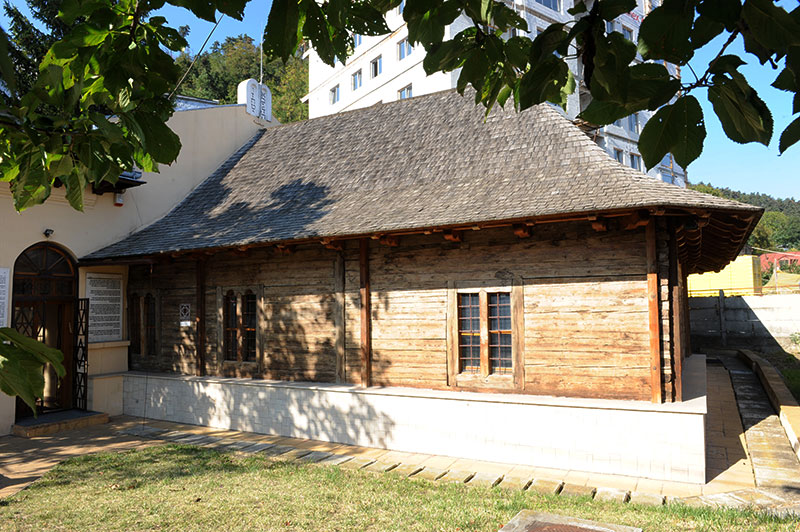 Holzsynagoge mit Dachschindeln aus Holz und einem Neubaublock im Hintergrund