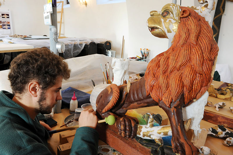 Ein Mann restauriert eine alte Holzfigur