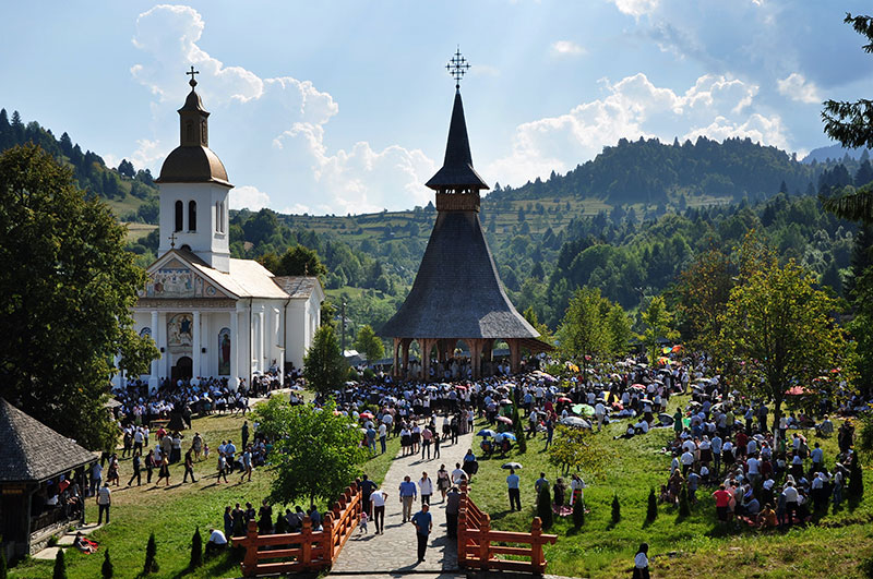 offene Kirche neben einer Steinkirche mit vielen Menschen