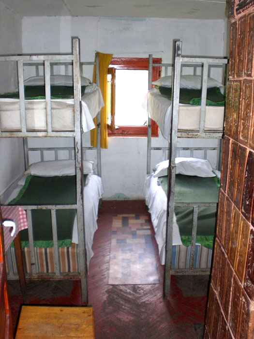 Zwei Metalldoppelstockbetten und Kachelofen in einem kleinen Zimmer