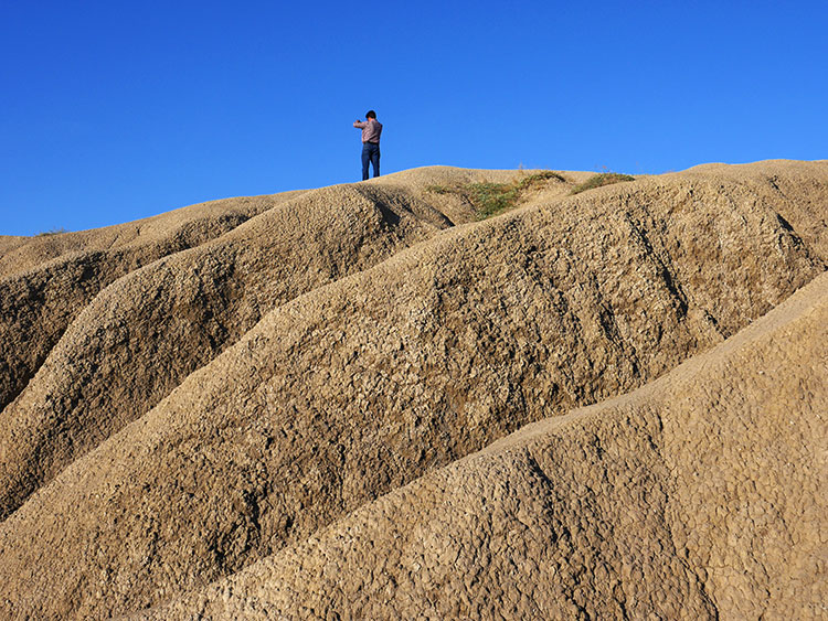 Mann steht auf dem getrockneten Vulkankegel und fotografiert