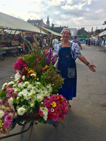 Blumenverkäuferin  auf dem Markt vor ihrem Blumenwagen