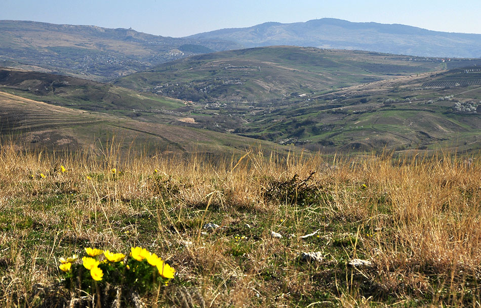 Hügelkette mit einigen Bergen und Dörfern in der Ferne