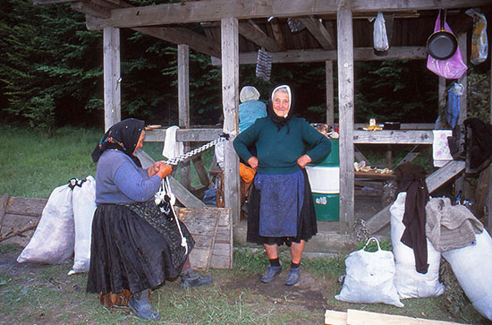 Foto 2 Frauen vor einem Holzuunterstand mit weißen Plastesäcken