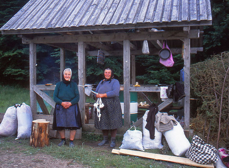 Foto 2 Frauen vor einem Holzuunterstand mit weißen Plastesäcken