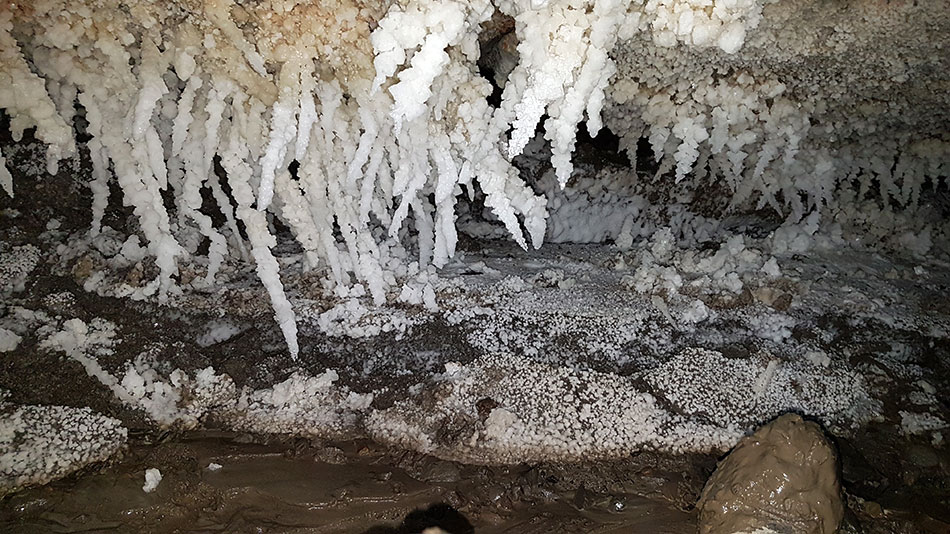Salzkristalle in einer Höhle mit schlammverschmiertem Schuh
