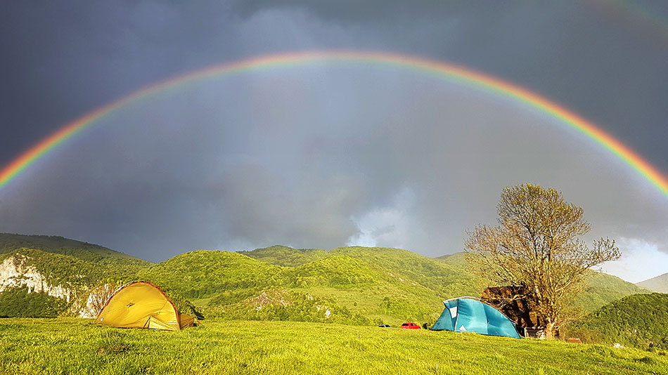 Zeltplatz mit Regenbogen im Hintergrund