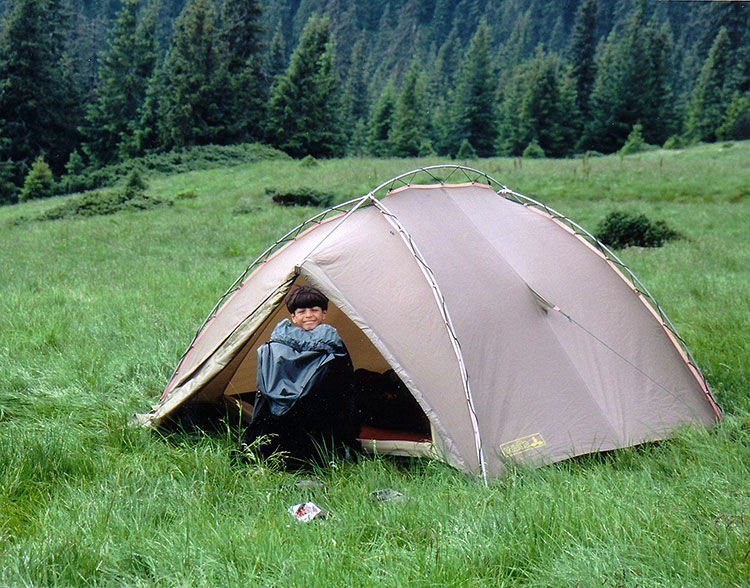 Foto von Michele mit Regenjacke im Zelteingang sitzend