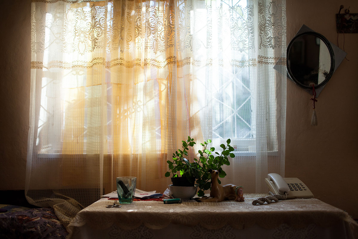 Tisch mit Blumen und Telefon vor Fenster