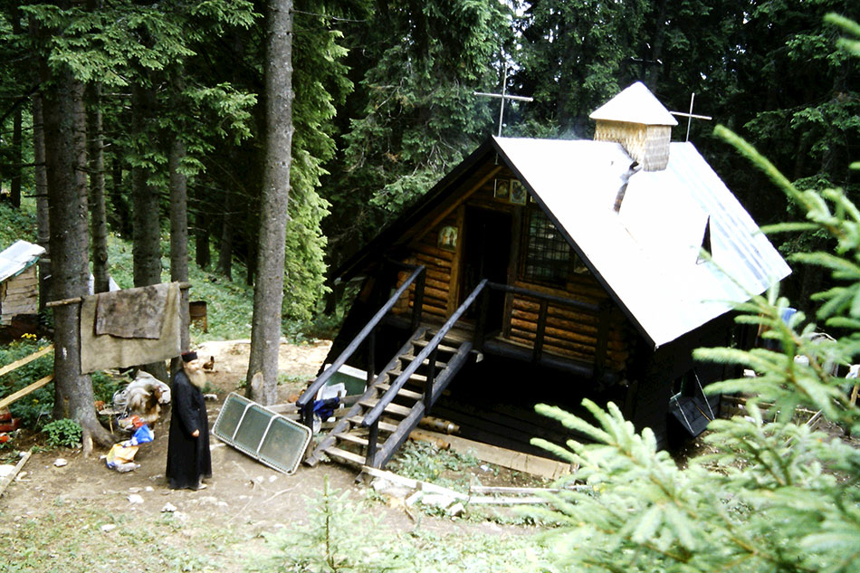 Eremit vor seinem Holzhaus im Wald