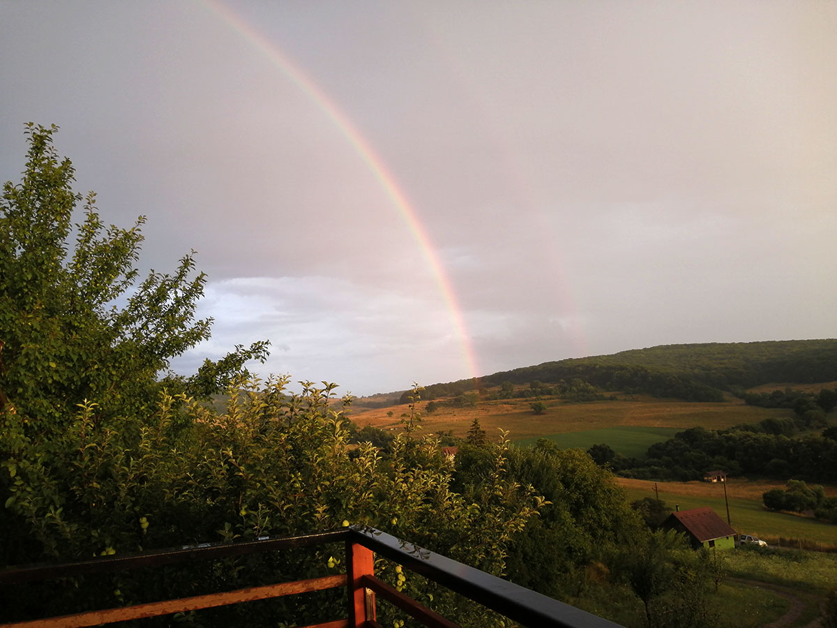 Regenbogen über einer hügeligen Berglandschaft