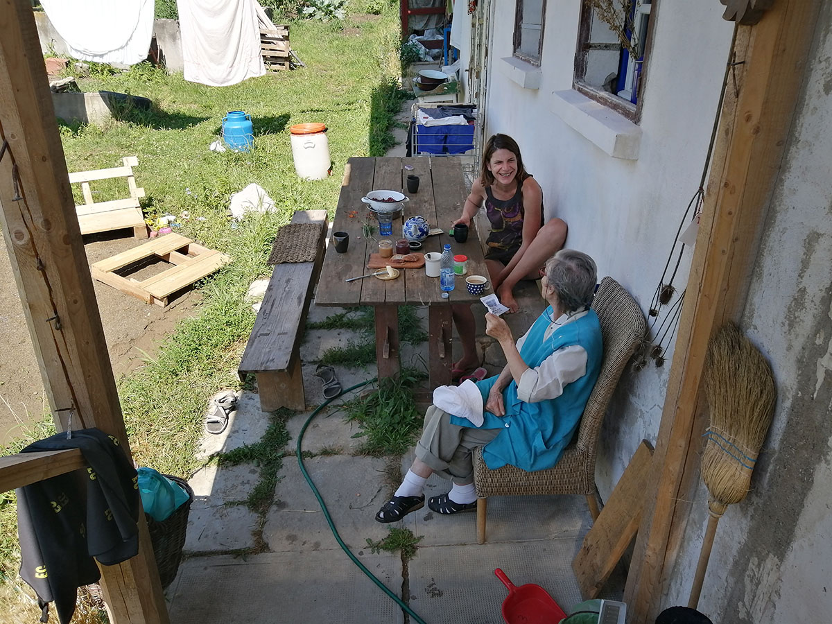 Anca sitzt mit einer Frau vor ihrem Haus