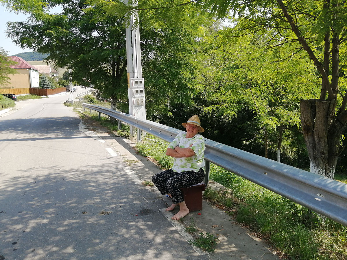 Frau sitzt am Straßenrand einer Dorfstraße