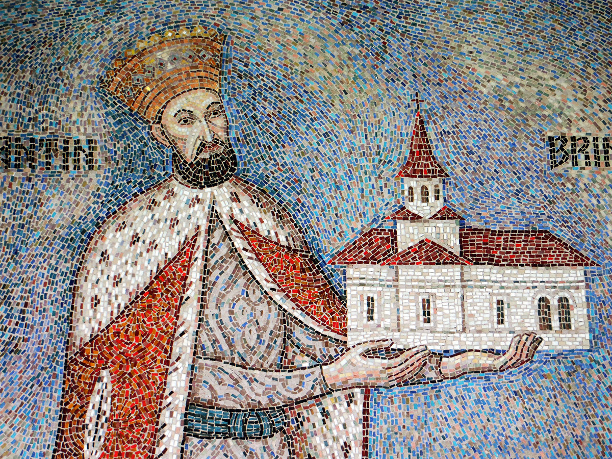 Wangemälde aus Mosaiksteinen mit einem Mönch welcher in der Hand eine Kirche hält